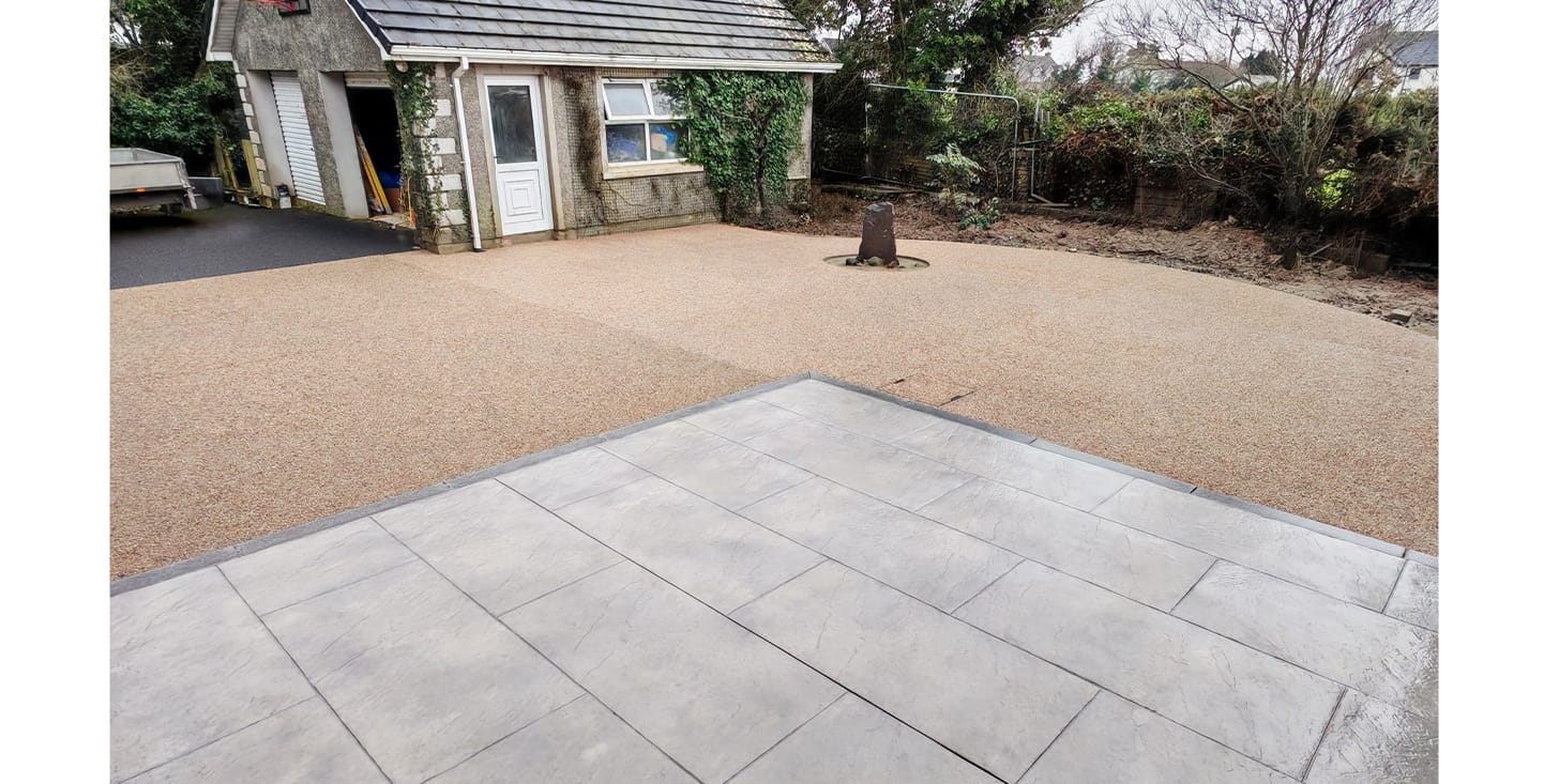 Contemporary outdoor area with exposed aggregate paving, stamped concrete patios, and stepped access to a garden room